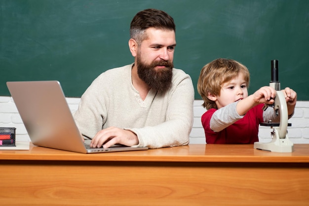 L'insegnante dell'uomo gioca con l'insegnante di homeschooling del bambino in età prescolare e lo scolaro usando il laptop in classe yo...