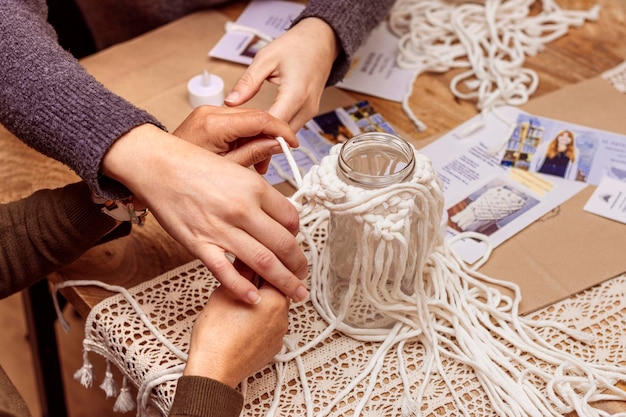 L'insegnante di macramè bianco aiuta il suo studente con l'arte tessile dei nodi di macramè