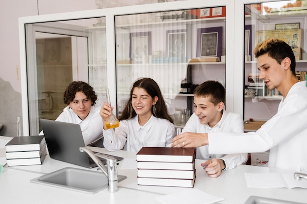 L'insegnante di scuola dà lezione di chimica ai bambini in un laboratorio con boccette con liquidi per esperimenti Concetto di educazione Lezione di gruppo di compagni di classe alla lezione di chimica