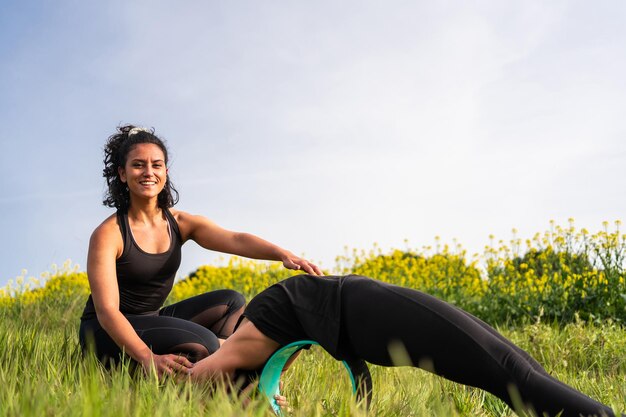 L'insegnante di yoga aiuta gli studenti a eseguire esercizi di yoga in natura con l'aiuto di un elemento yoga