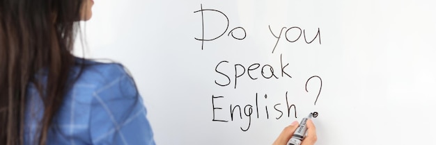 L'insegnante donna scrive con un pennarello parli inglese su una lavagna bianca come concetto di traduttore?
