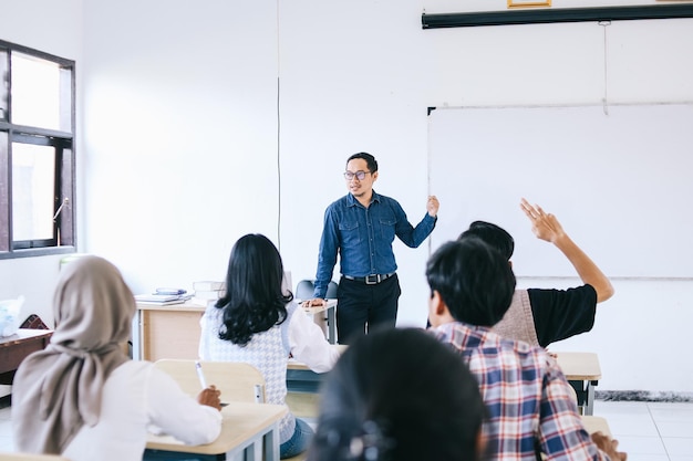 L'insegnante spiega qualcosa davanti all'aula Lo studente alza la mano con una domanda