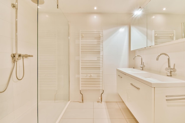 L'interno di un ampio bagno moderno in un accogliente appartamento residenziale con cabina doccia vetrata e doppio lavabo in ceramica