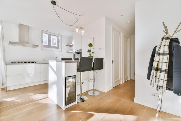 L'interno di un appartamento moderno con cucina e bar con zona pranzo in bianco su pavimento in parquet