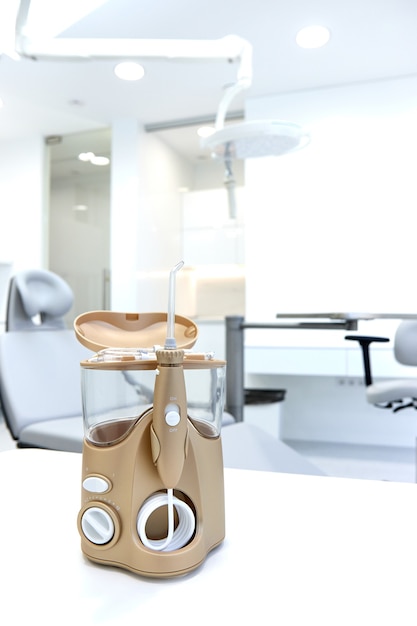 L'irrigatore a sprinkler dorato del dentista si trova su un tavolo su uno sfondo bianco brillante