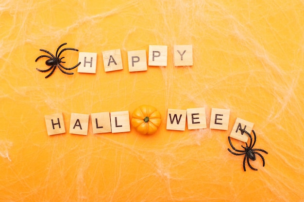L'iscrizione felice halloween con ragnatela e ragni su sfondo arancione