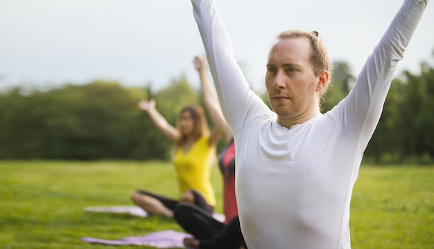 L'istruttore di yoga mostra l'esercizio di flessibilità per un gruppo di ragazze nel parco, estate