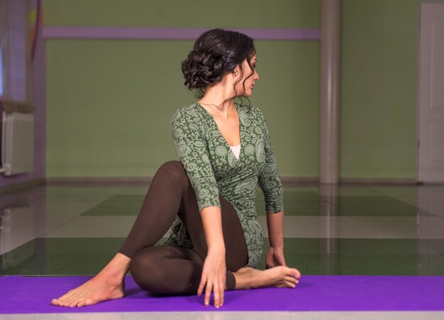 L'istruttore di yoga pone le posizioni di yoga./Il maestro di yoga allunga le pose di yoga in palestra.