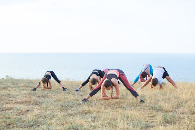 L'istruttore forma i bambini di yoga nelle montagne sull'oceano.