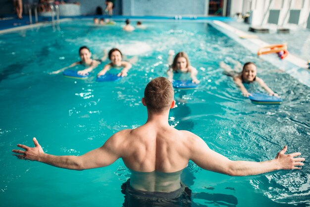 L'istruttore maschio lavora con il gruppo femminile sull'allenamento in piscina. Corsi di acquagym, sport acquatici