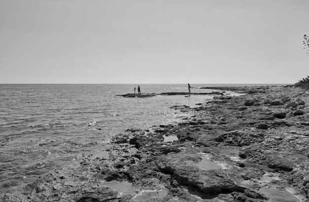 L'Italia, Sicilia, Mar Mediterraneo, Portopalo, persone sulla costa rocciosa orientale meridionale siciliana