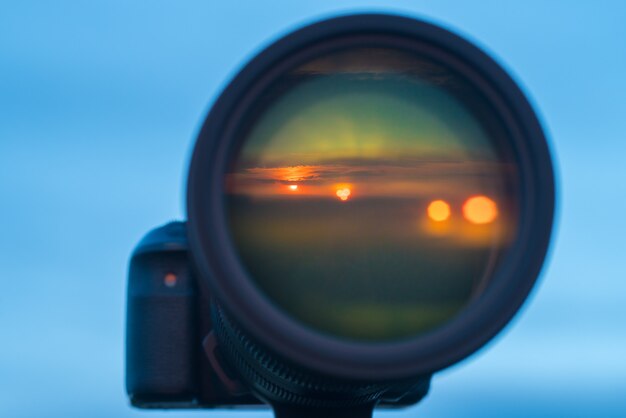 L'obiettivo della fotocamera con un riflesso del tramonto sullo sfondo del cielo