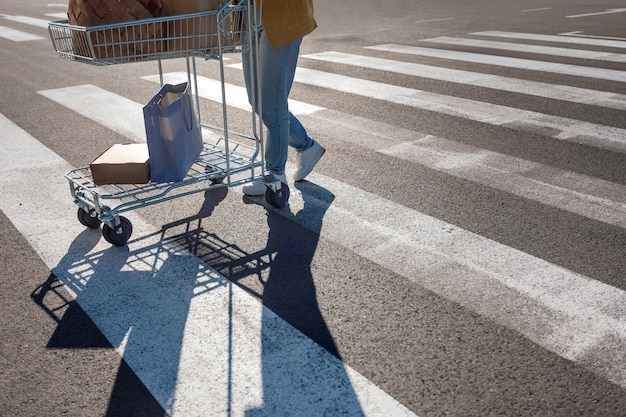 L'ombra della donna cammina con il carrello sulle strisce pedonali contrassegnate