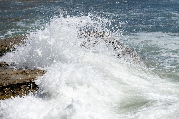 L'onda spruzzata rotola sulle rocce dell'oceano