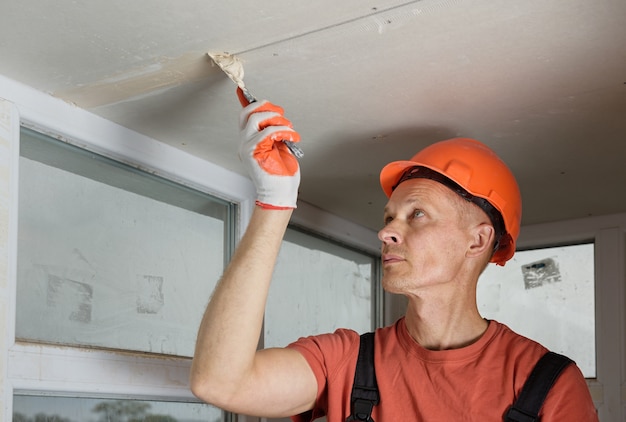 L'operaio che riempie le lastre di cartongesso esegue le cuciture dello stucco di gesso