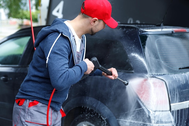 L'operaio della lavanderia sta lavando l'auto dei clienti.