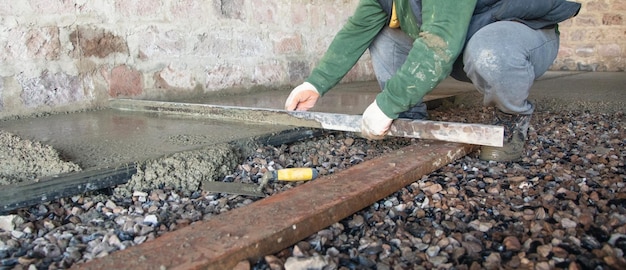 L'operaio edile allinea il pavimento del massetto in cemento