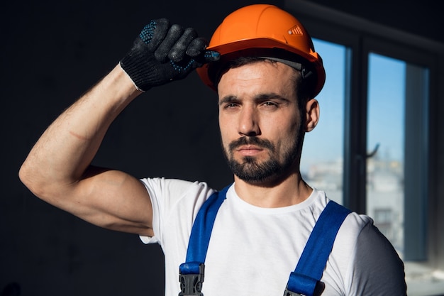 L'operaio in tuta blu e camicia bianca tiene il casco con la mano