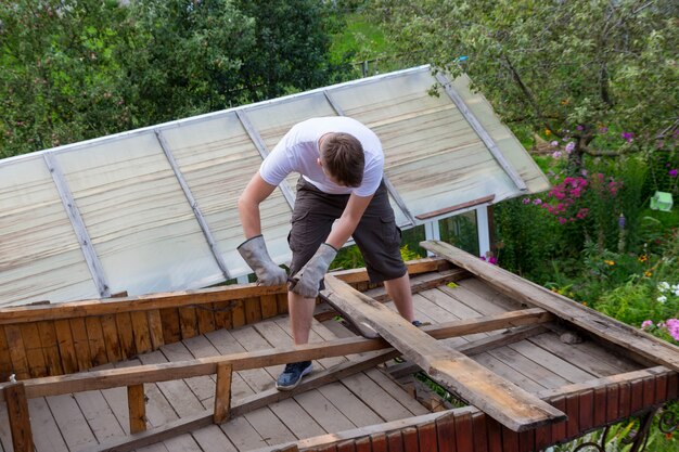 L'operaio rimuove le vecchie assi dal tetto, la casa è in fase di ristrutturazione.