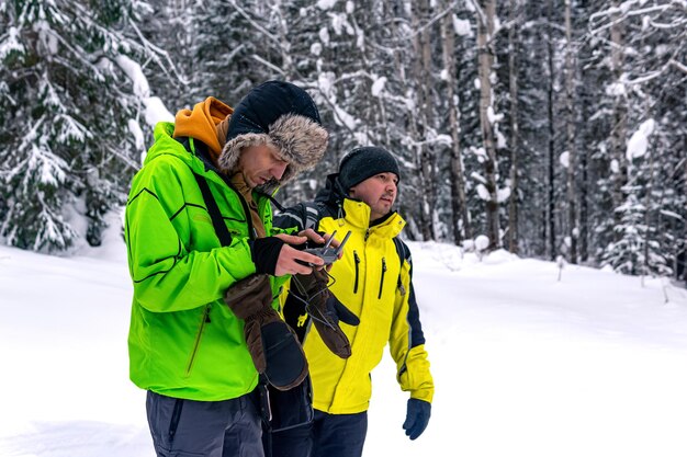 L'operatore con assistente controlla un drone da una foresta invernale