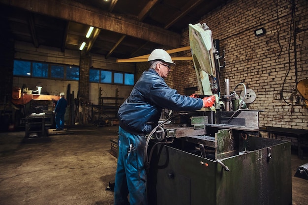 L'operatore della fabbrica di metalli controlla la macchina utensile per il taglio dell'acciaio.