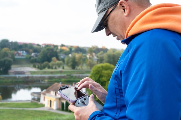 L'operatore tiene in mano il telecomando del drone Un agricoltore utilizza un quadricottero per lavorare in una struttura industriale Telecomando con smartphone in mano agricoltura moderno concetto di business