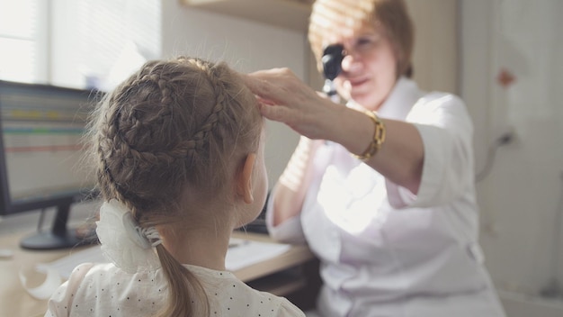 L'optometrista della donna in clinica controlla la vista all'oftalmologia del bambino della bambina