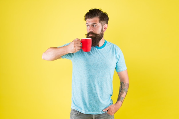 L'ora del tè. Caffè con la giusta proporzione di latte. Stile di vita delle abitudini mattutine. Fanatico della cultura del caffè. Concetto di energia. Sfondo giallo barista hipster. Caffetteria. L'uomo barbuto beve il caffè mattutino.