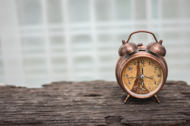 L&#39;orologio classico è posto su un vecchio tavolo con uno sfondo bianco.