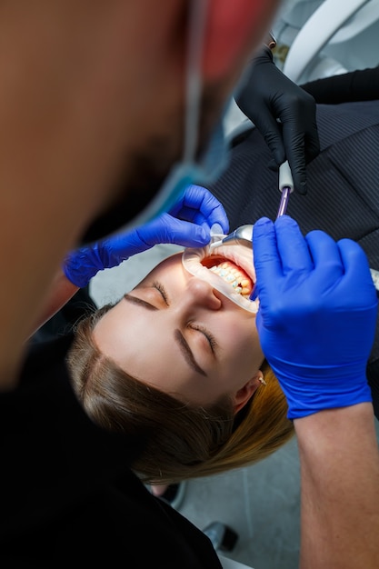 L'ortodontista mette bretelle metalliche sui denti del paziente. Trattamento odontoiatrico ortodontico. Foto di alta qualità