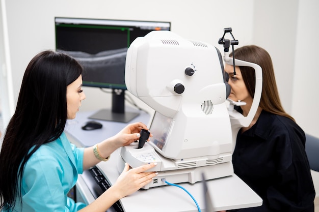 L'ottico optometrista bruna sta diagnosticando la donna su attrezzature moderne speciali Clinica aggiornata per occhi sani Primo piano