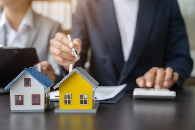 L'ufficiale del mutuo per la casa utilizza una calcolatrice con un piano casa