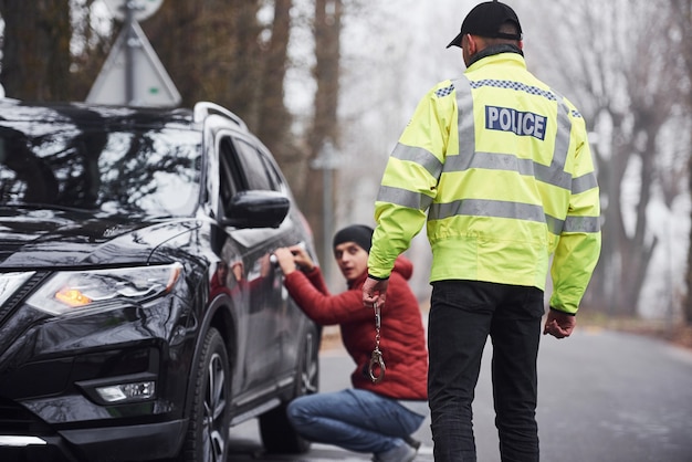 L'ufficiale di polizia in uniforme verde ha scoperto un furto d'auto per strada.