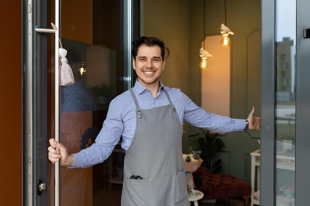 L'unico proprietario è lieto di accogliere i clienti all'ingresso del suo negozio o bar con un sorriso sulle labbra