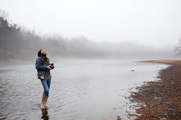 L'uomo a tutta lunghezza nel lago contro il cielo durante l'inverno
