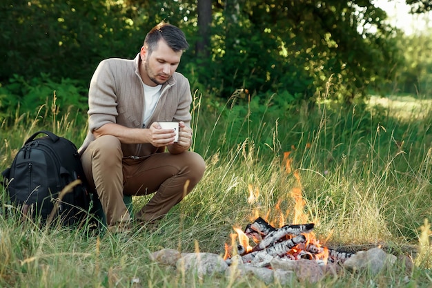 l'uomo accanto al fuoco sulla natura verde.