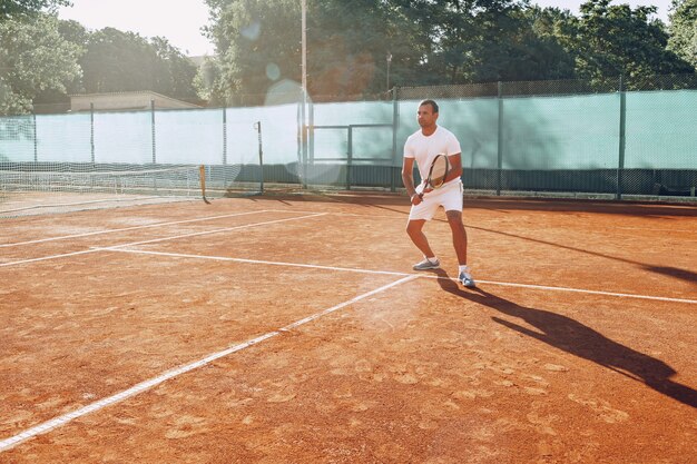 L'uomo adatto gioca a tennis sul campo da tennis