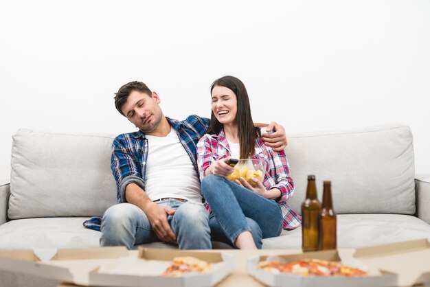 L'uomo addormentato e una donna si siedono sul divano sullo sfondo del muro bianco