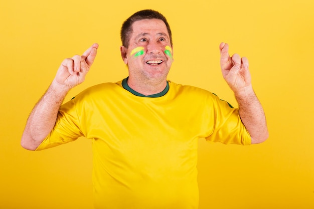 L'uomo adulto brasiliana tifoso di calcio ha incrociato le dita segno di fortuna che desidera la foto del primo piano