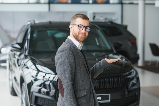 L'uomo adulto cliente maschio cliente acquirente indossa abito classico camicia bianca sceglie auto vuole comprare nuova automobile touch controllo auto in showroom veicolo salone concessionaria negozio motor show indoor Concetto di vendita