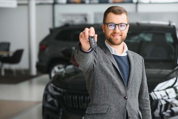 L'uomo adulto cliente maschio cliente acquirente indossa abito classico camicia bianca sceglie auto vuole comprare nuova automobile touch controllo auto in showroom veicolo salone concessionaria negozio motor show indoor Concetto di vendita