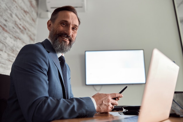 L'uomo adulto felice sta lavorando in un armadio per ufficio moderno