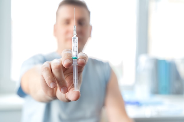 L'uomo, adulto nello studio del medico è vaccinato. Siringa con vaccino contro il coronavirus covid-19, influenza, malattie infettive pericolose.Iniezione dopo studi clinici per uomo, bambino.Concetto di medicina.