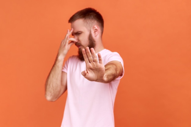 L'uomo afferra il naso facendo una smorfia di disgusto e mostrando un gesto di arresto che esprime repulsione a puzzare