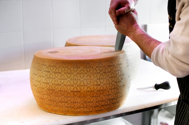 L'uomo affettare apre una ruota di formaggio Grana Padano