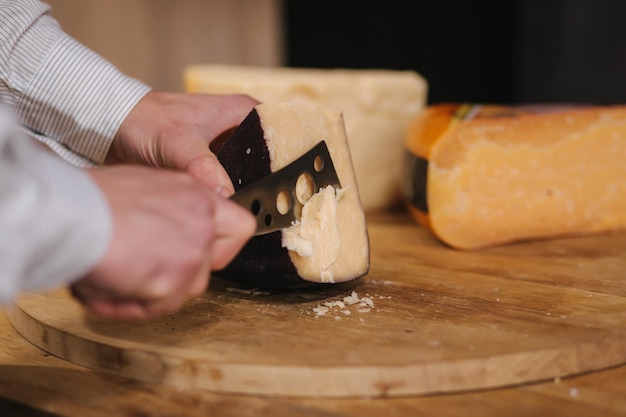 L'uomo affettare un pezzetto di formaggio per il gusto Il giovane lavoratore usa un coltello speciale per il formaggio