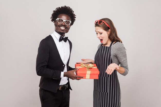 L'uomo africano orgoglioso fa un regalo alla sua donna per San Valentino. Foto in studio, sfondo grigio