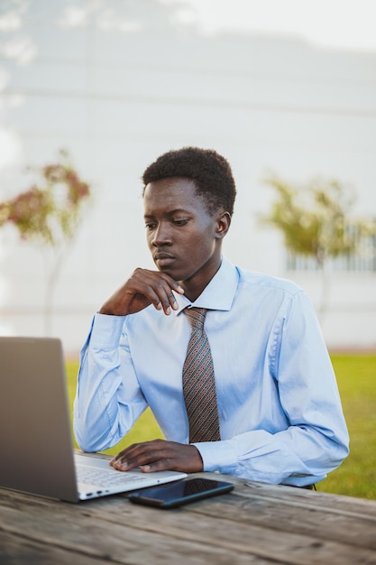 L'uomo africano sembra concentrato mentre lavora al suo laptop in un'area picnic