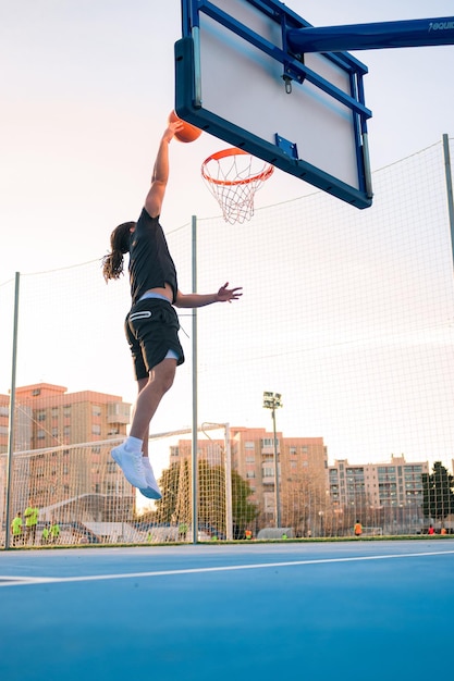 L'uomo afro latino salta e schiaccia la palla su un campo da basket