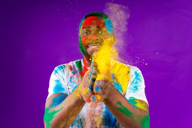 L'uomo afroamericano celebra il festival di holi sullo sfondo viola dello studio